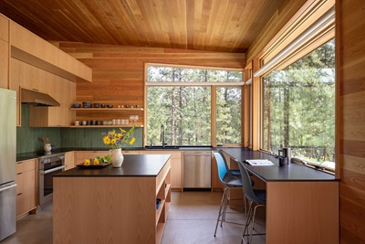 A kitchen featuring lots of wood,  green backsplash, and large Marvin Ultimate Specialty Shape windows.