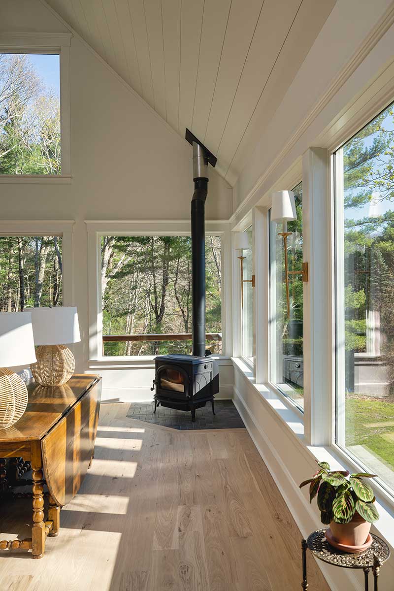 A wood-fired stove in a traditional living room, surrounded by Marvin Elevate Direct Glaze windows.