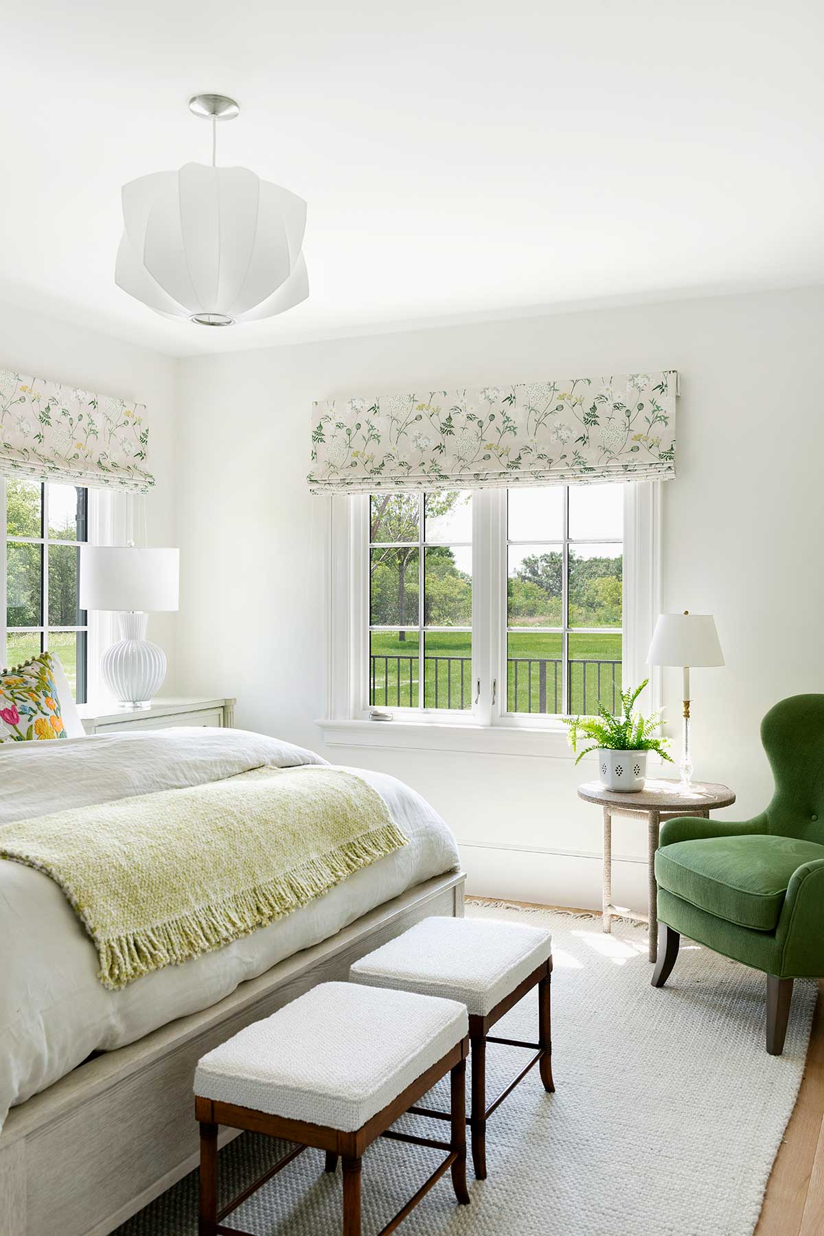 A bedroom overlooking lush green grass through Marvin Ultimate Casement Narrow Frame windows with window treatments above.