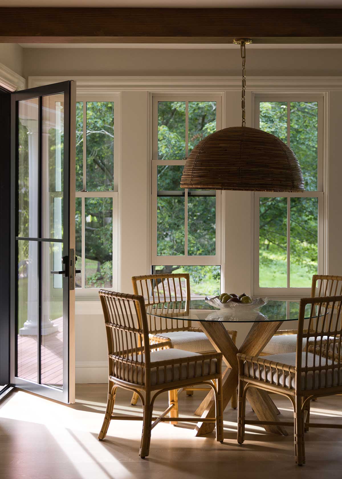 A dining area with Marvin Ultimate Inswing doors and Ultimate Double Hung G2 windows overlooking lush greenery.